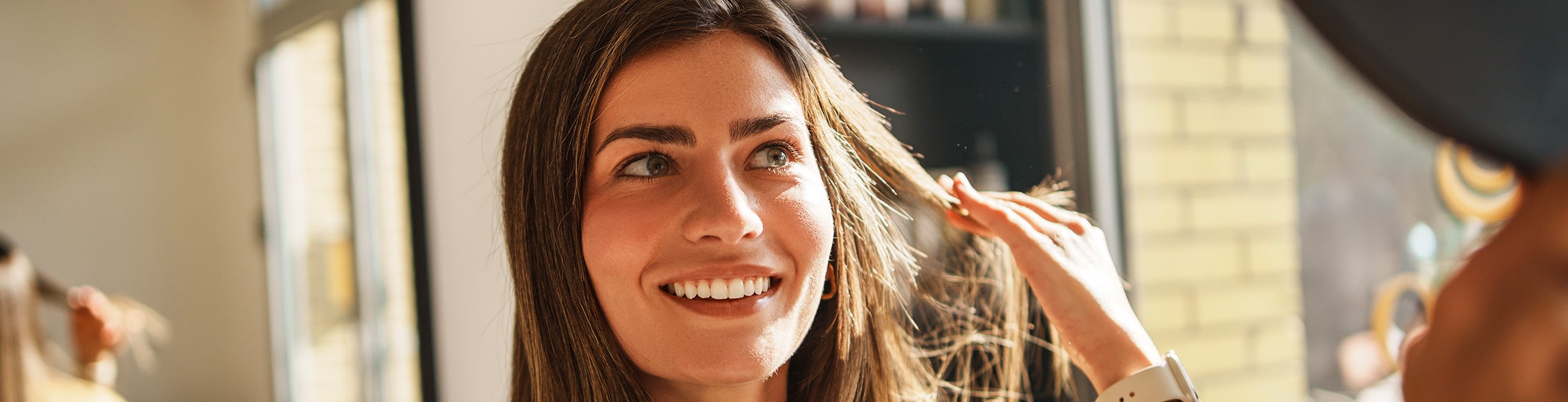 Woman checking her healthy-looking hair in the mirror as part of a routine to maintain hair volume and strength.